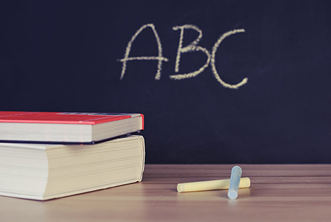 Lissone - lavagna con scritta ABC, gessetti e libri appoggiati su una cattedra